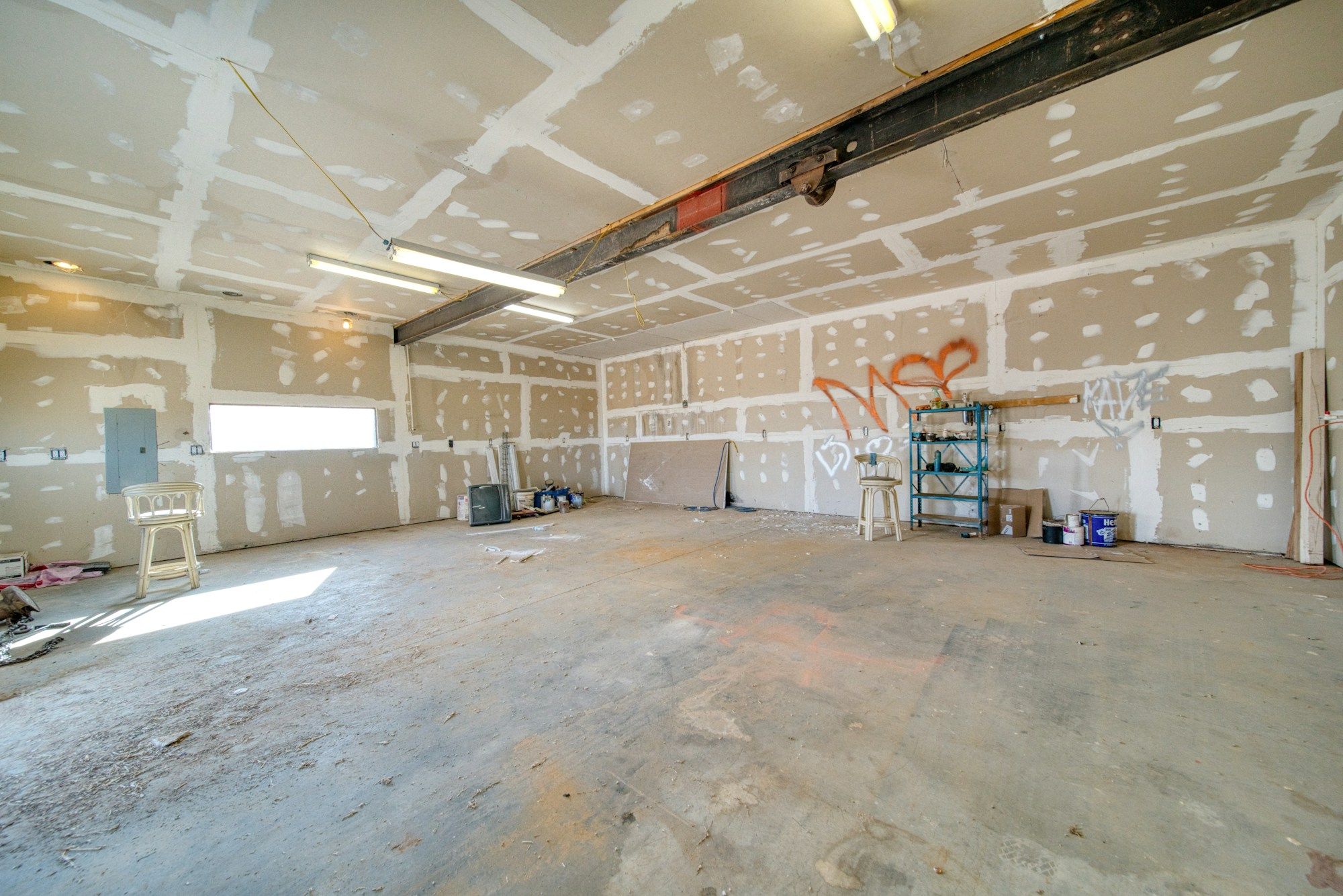 Large room with taped and mudded drywall on the walls and ceiling