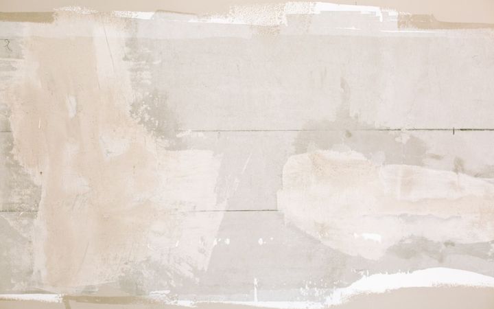 Unfinished wall with patches of joint compound over old paint