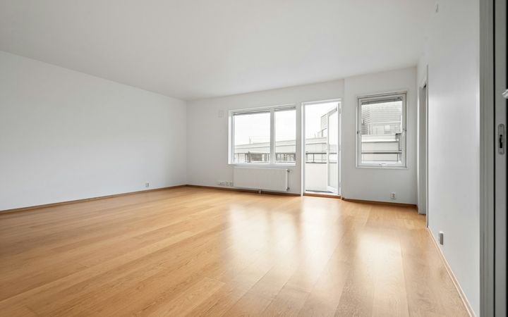 Empty apartment room with white walls and hardwood floors