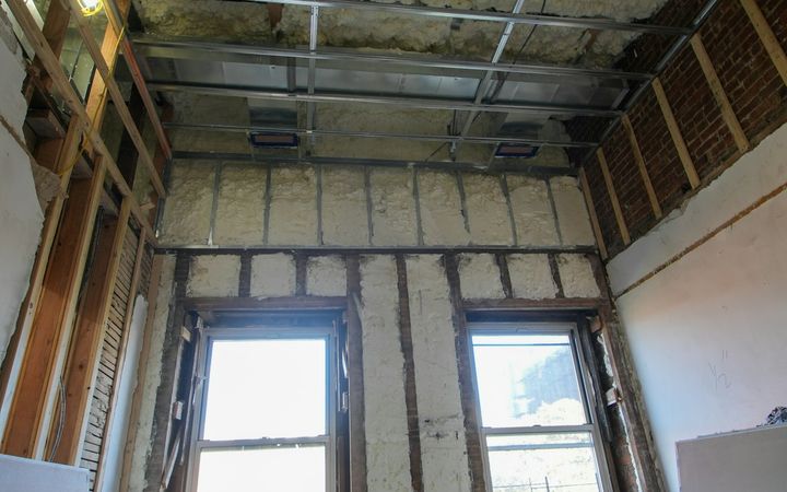 Room with insulation between exposed studs and open ceiling framing