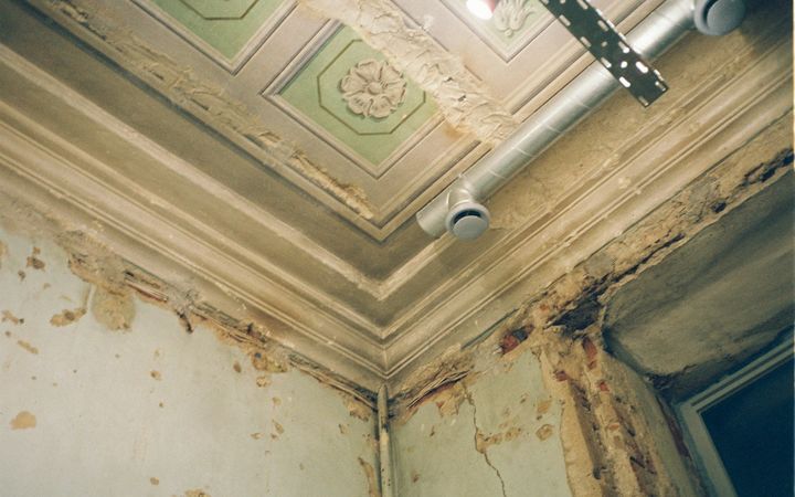 Old plaster ceiling with water stains and peeling paint along the cornice
